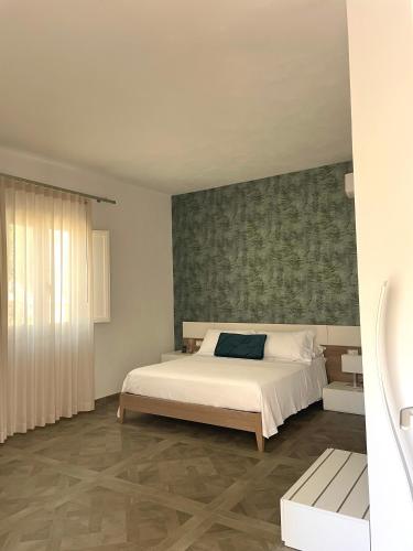 a bedroom with a white bed and a green wall at B&B SoleLuna in Lampedusa