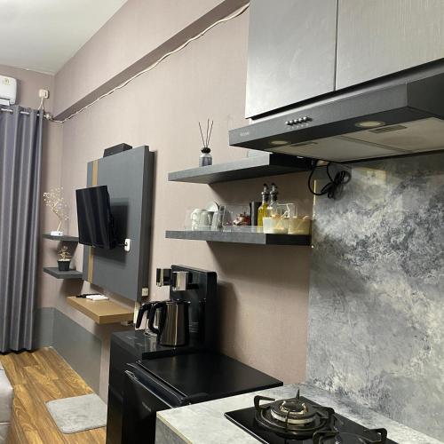 a kitchen with a black stove and a microwave at Apartemen Bale Hinggil Studio in Medokansemampir