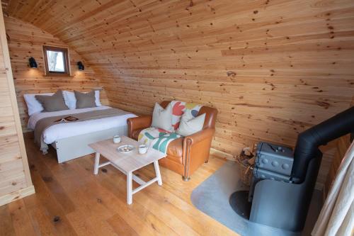 a room with a bed and a stove in a log cabin at Glamping Pod 1 Comfort in Scarborough