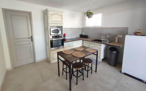 Una pequeña cocina con una mesa y un refrigerador. en LES JARDINS D'ORANGE, en Orange