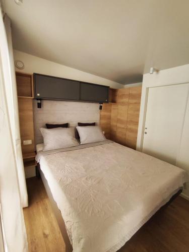 a bedroom with a large white bed with a headboard at Mobile home Kala in Biograd na Moru