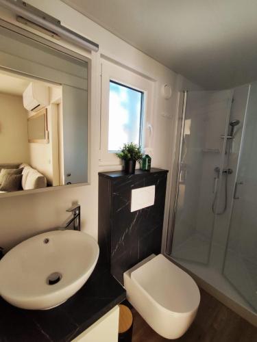 a bathroom with a sink and a shower and a toilet at Mobile home Kala in Biograd na Moru