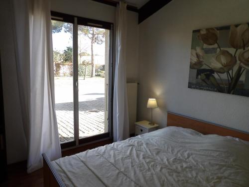 een slaapkamer met een bed en een groot raam bij Appartement 4 personnes avec terrasse au golf de St Cyprien in Saint-Cyprien