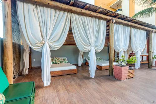a bedroom with white drapes on a porch at Pousada Praia Bela in Ilhéus