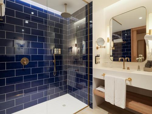 a blue tiled bathroom with a sink and a mirror at H10 Porto Poniente 4* Sup in Benidorm