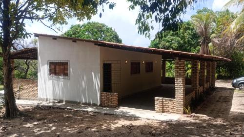una pequeña casa blanca con una pared de ladrillo en Quintas da Lagoa Azul, en Nísia Floresta