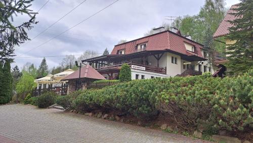 a large house with a red roof on a hill at Zajazd-restauracja Zyga in Iwkowa