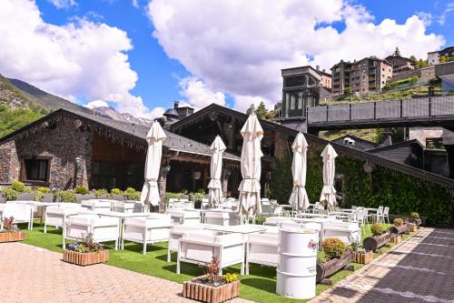 a restaurant with white tables and white umbrellas at Hotel AnyosPark Mountain & Wellness Resort in Anyós