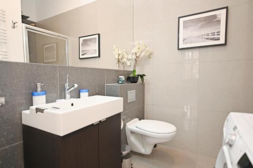 a bathroom with a white sink and a toilet at Victus Apartamenty, Apartament Niebieski in Sopot