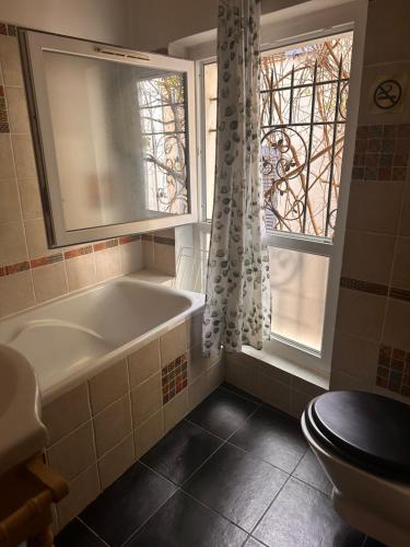 a bathroom with a tub and a window and a toilet at Lou Couquet in Antibes