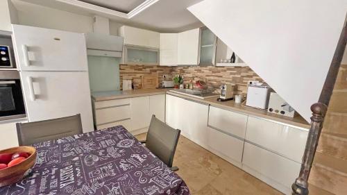 - une cuisine avec des placards blancs et une table avec un bol de fruits dans l'établissement Hameau de Guerrevieille, à Grimaud