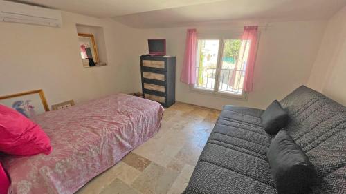 une chambre avec un lit, un canapé et une fenêtre dans l'établissement Hameau de Guerrevieille, à Grimaud