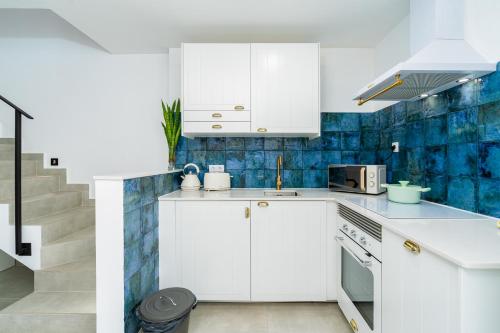 a kitchen with white cabinets and blue tiles at Casa Baco- Cozy House City Center in Lagoa