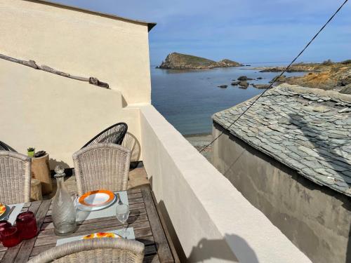 einen Tisch und Stühle auf einem Balkon mit Meerblick in der Unterkunft La Vue 360 in Centuri