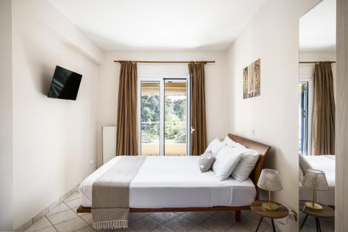 a white bedroom with a bed and a window at Villa Nina with Private Plunge Pool, 5km to Corfu Town in Corfu Town