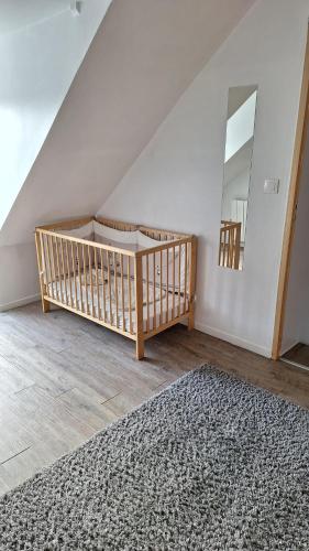 a room with a crib and a rug and a mirror at Maison de la Grève in Ouistreham
