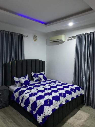 a bedroom with a blue and white comforter on a bed at Stobi Apartment in Abuja