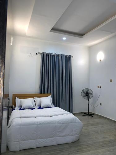 a bedroom with a large white bed and a window at Stobi Apartment in Abuja