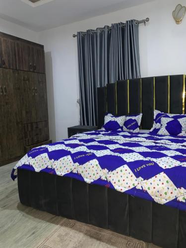 a bed with a blue and white quilt on it at Stobi Apartment in Abuja