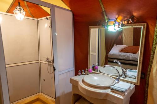 a bathroom with a sink and a shower and a mirror at Khamlia Desert Luxury Camp in Merzouga