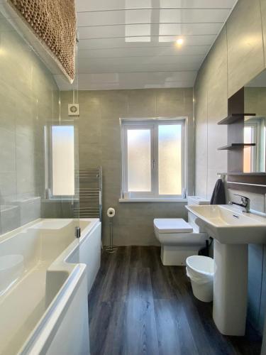 a bathroom with two sinks and a tub and a toilet at Bailey’s Townhouse in Belfast