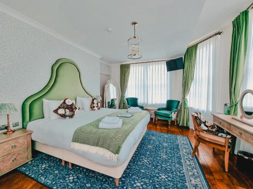 een slaapkamer met een groot bed met een groen hoofdeinde bij The Swan Hotel in Staines