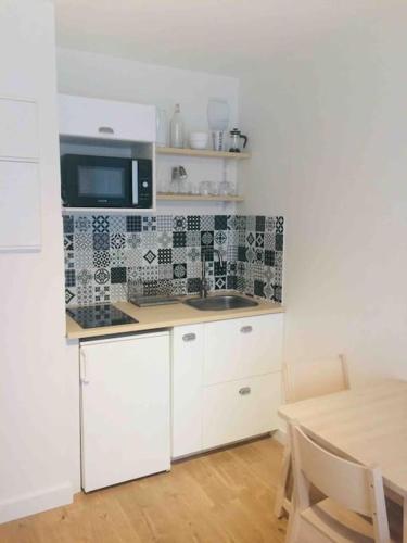 - une cuisine avec des placards blancs, un four micro-ondes et une table dans l'établissement Nantes gare , Studio proche Cathédrale / IUT, à Nantes