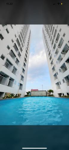 two large white buildings with a swimming pool between them at Mansyur Residence Apartment Medan in Sunggal