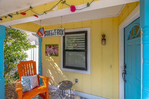 uma casa amarela com uma porta azul e uma cadeira em The Squeezebox em Saint Simons Island