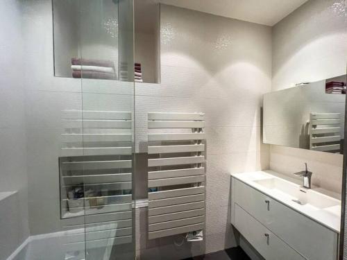 uma casa de banho com uma cabina de duche em vidro e um lavatório. em 16th District Spacious Sophistication em Montreuil