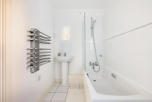 uma casa de banho branca com um chuveiro e um lavatório. em The Morden Collection em Londres
