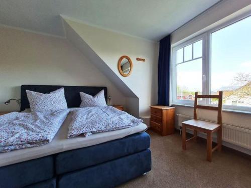 a bedroom with a bed and a chair and a window at Doppelhaushaelfte-Kornblume in Presen