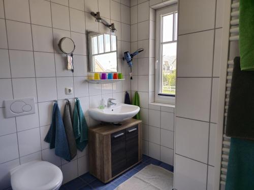 a bathroom with a sink and a toilet and a window at Doppelhaushaelfte-Kornblume in Presen