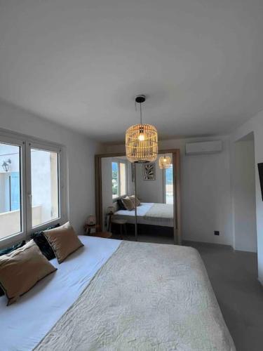 une chambre avec un grand lit et un lustre dans l'établissement Magnifique Villa piscine vues mer, lac et montagnes, à Santa-Reparata-di-Balagna
