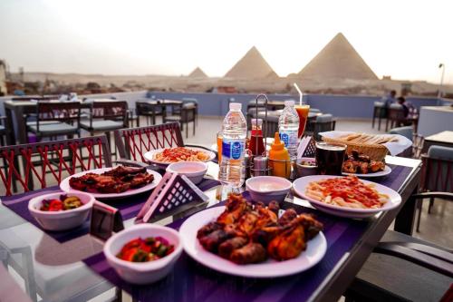 Pyramids Sun Land Veiw في القاهرة: طاولة مع أطباق من الطعام على طاولة مع الاهرامات