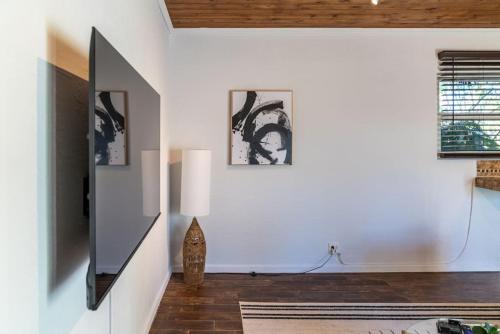a living room with white walls and a flat screen tv at Hidden Gem Off Atlantic Ave, Just Steps From Beach in Delray Beach