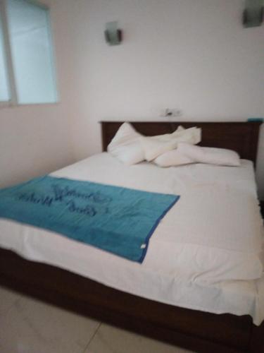 a bed with a blue blanket on top of it at Navai Guest House in Batticaloa
