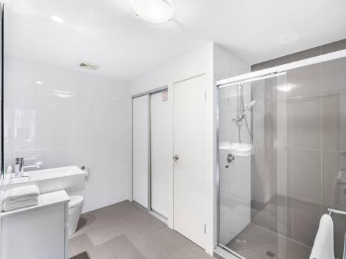 a bathroom with a shower and a toilet and a sink at Chic Modern Retreat 1BR Apt w pool Kelvin Grove in Brisbane