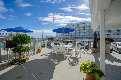 a patio with white chairs and blue umbrellas at Fleur de Lis Beach Motel in Wildwood Crest