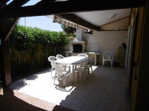 un patio avec une table et des chaises et une cuisine dans l'établissement HOLIDAYLAND 302 VILLA T3 MEZZANINE 8 couchages climatisé NARBONNE PLAGE, à Narbonne-Plage