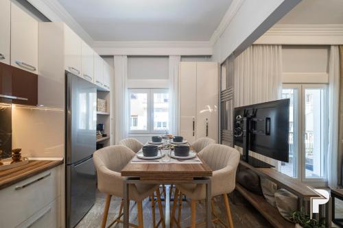 eine Küche mit einem Tisch mit Stühlen und einem TV in der Unterkunft P deluxe suites 4 in Thessaloniki