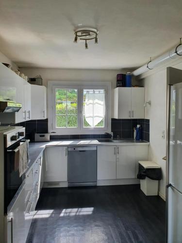 een grote keuken met witte kasten en een raam bij Maison de 5 chambres avec jardin clos et wifi a Dammartin en Goele in Dammartin-en-Goële
