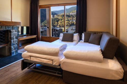 sala de estar con 2 camas, sofá y chimenea en Aparthotel AnyosPark Mountain & Wellness Resort en Anyós