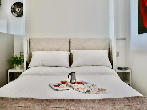 a bed with a tray with a tea kettle and two cups at Portopiccolo Apartments - Loggia sul mare in Sistiana