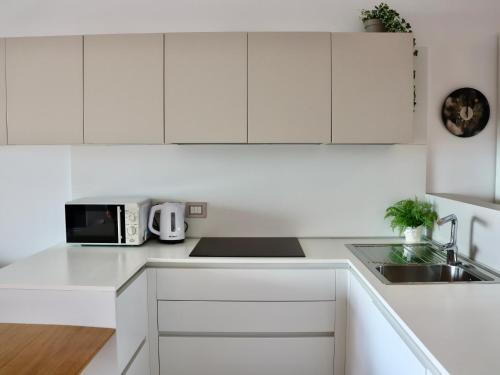 a white kitchen with a sink and a microwave at Portopiccolo Apartments - Loggia sul mare in Sistiana