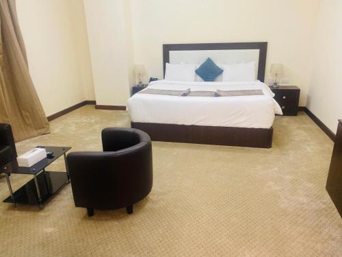 a bedroom with a large bed and a chair at A Line Hotel in Doha