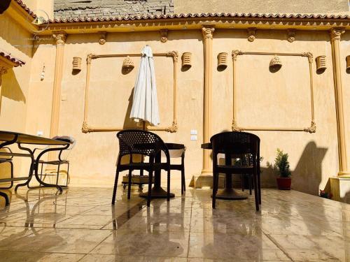 een kamer met 2 stoelen, een tafel en een paraplu bij Sidi Hamad Pyramids INN in Caïro