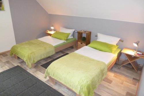 een kamer met 2 bedden met groene lakens en houten vloeren bij Ferienwohnung Uni Koblenz in Koblenz