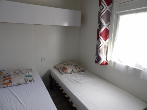 deux lits dans une petite pièce avec une fenêtre dans l'établissement St Cyprien Mobil home 6 personnes Linge inclus, à Saint-Cyprien