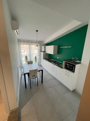 a kitchen with a table and a green wall at Casa vacanza Le Isole in Marta